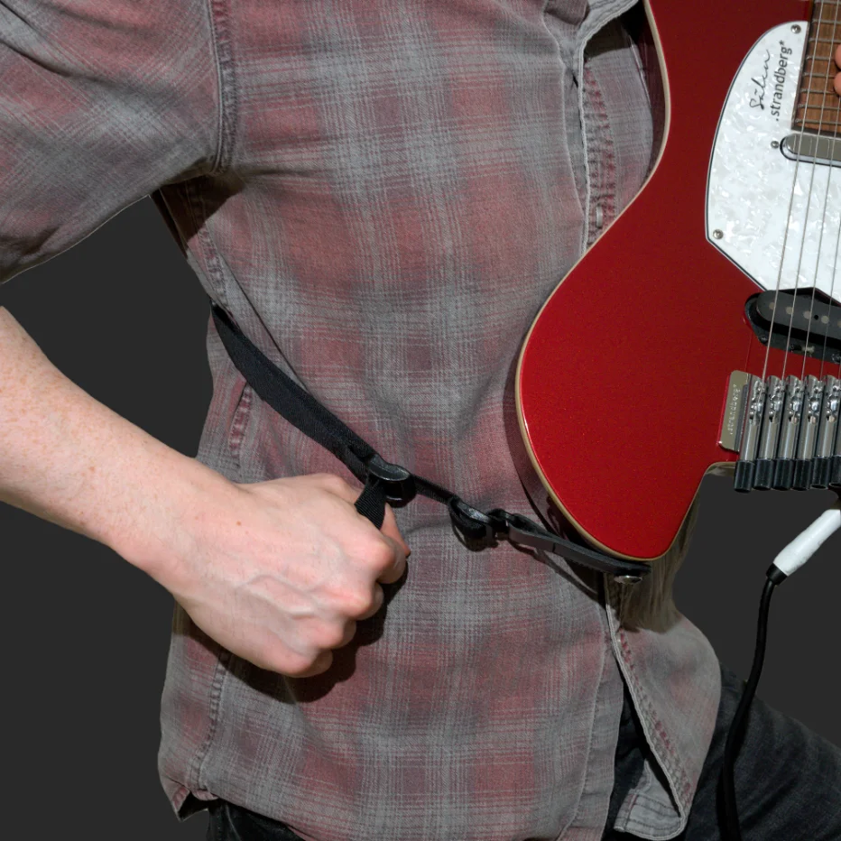 Guitarist seated, strap resting across their leg